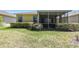 Home's backyard featuring a screened-in lanai and expansive grassy area at 4500 Golf Club Ln, Spring Hill, FL 34609