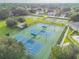 Aerial view of community tennis and basketball courts surrounded by lush landscaping in a residential neighborhood at 4500 Golf Club Ln, Spring Hill, FL 34609