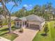 Charming single-Gathering home featuring a brick driveway, two-car garage, a cozy porch, and manicured landscaping at 4910 Southern Valley Loop, Brooksville, FL 34601