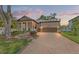 Charming single-Gathering home featuring a brick driveway, two-car garage, a cozy porch, and manicured landscaping at 4910 Southern Valley Loop, Brooksville, FL 34601