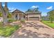 Charming single-Gathering home featuring a brick driveway, two-car garage, a cozy porch, and manicured landscaping at 4910 Southern Valley Loop, Brooksville, FL 34601