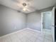 This bedroom is painted with light grey walls, tile flooring and has a ceiling fan at 5147 Larch Ln, New Port Richey, FL 34653