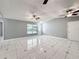 Spacious living room featuring tile flooring, large windows, neutral walls, and ceiling fans at 5147 Larch Ln, New Port Richey, FL 34653