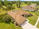 Aerial view of a well-maintained home with green lawn, mature trees, and a golf course in the background at 5164 Golf Club Ln, Spring Hill, FL 34609