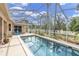 A refreshing screened-in pool area surrounded by lush landscaping with blue patio furniture at 5638 Hereford Dr, New Port Richey, FL 34655