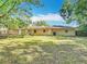 Large, grassy backyard and the home's exterior, showing back patio with a sliding door at 6203 Sumter Dr, Brooksville, FL 34602