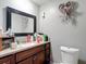 A bathroom with a granite vanity, a mounted mirror, and a standard toilet at 6203 Sumter Dr, Brooksville, FL 34602
