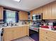 Well-equipped kitchen with stainless steel oven and microwave, wood cabinets, and laminate floors at 6203 Sumter Dr, Brooksville, FL 34602