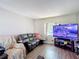 Living area with a large flat screen television, wood-look floors, and a leather sofa at 6203 Sumter Dr, Brooksville, FL 34602