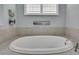 Bright bathroom featuring a soaking tub with plantation shutters and beach-themed artwork at 7495 Birdland Cres, Spring Hill, FL 34607
