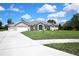 Charming single-story home featuring a well-manicured lawn, a three car garage and a welcoming entryway at 7495 Birdland Cres, Spring Hill, FL 34607