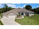 Inviting single-story home boasts a three-car garage, mature landscaping, and a graceful arched entryway at 7495 Birdland Cres, Spring Hill, FL 34607