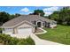 Attractive single-story home featuring a three-car garage, lush landscaping, and an arched front entrance at 7495 Birdland Cres, Spring Hill, FL 34607