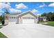 Three-car garage with white doors, concrete driveway, and partial view of the landscaped front yard at 7495 Birdland Cres, Spring Hill, FL 34607
