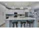 Bright and airy kitchen featuring a large island with seating, white cabinets, and modern chandeliers at 7495 Birdland Cres, Spring Hill, FL 34607