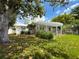 Charming home featuring a beautiful white pergola and a well-manicured lawn surrounded by lush greenery at 75 N Canal Dr, Palm Harbor, FL 34684