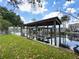 Covered boat dock with metal roof, surrounded by calm canal waters and lush green grass at 75 N Canal Dr, Palm Harbor, FL 34684