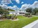 Inviting two-story home featuring manicured landscaping, blooming roses, and a charming front porch at 75 N Canal Dr, Palm Harbor, FL 34684