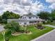 Spacious home featuring manicured landscaping, blooming roses, and a charming front porch at 75 N Canal Dr, Palm Harbor, FL 34684