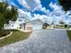 Exterior view of home featuring a brick driveway, two-car garage, and well-maintained lawn at 75 N Canal Dr, Palm Harbor, FL 34684