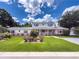 Charming two-story home with well-manicured lawn, brick accents, and beautiful flower beds at 75 N Canal Dr, Palm Harbor, FL 34684