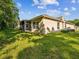 View of home's backyard with lush green grass and screened in patio at 7616 Wimpole Dr, New Port Richey, FL 34655