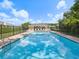 A serene swimming pool with clear blue water, surrounded by lounge chairs and a covered patio area at 7616 Wimpole Dr, New Port Richey, FL 34655