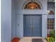 Close-up of the stately blue double front doors framed by an arched window and manicured landscaping at 8514 Ashbury Dr, Hudson, FL 34667