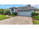 Two-car garage with a brick paver driveway and well-maintained landscaping at 8514 Ashbury Dr, Hudson, FL 34667