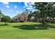 Expansive backyard with lush lawn, mature trees, and screened lanai for outdoor relaxation and entertaining at 888 Royal Birkdale Dr, Tarpon Springs, FL 34688