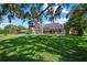 A spacious backyard features a screened lanai, mature trees casting shadows, and a lush lawn at 888 Royal Birkdale Dr, Tarpon Springs, FL 34688
