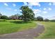 Scenic view of a home backing onto the lush green golf course with mature trees and a smooth cart path at 888 Royal Birkdale Dr, Tarpon Springs, FL 34688