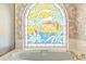 Close up of the stained glass window above a soaking tub in a bathroom with wallpaper at 888 Royal Birkdale Dr, Tarpon Springs, FL 34688