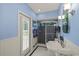 Bright blue bathroom with tiled shower, white fixtures, and wainscoting at 888 Royal Birkdale Dr, Tarpon Springs, FL 34688