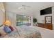 Bright bedroom with a view of the pool through sliding glass doors and features a ceiling fan and dresser at 888 Royal Birkdale Dr, Tarpon Springs, FL 34688