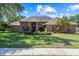 Charming brick home featuring mature trees, manicured lawn, and beautifully landscaped grounds at 888 Royal Birkdale Dr, Tarpon Springs, FL 34688