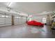 Spacious garage with multiple doors, windows, and a car covered in a red tarp at 888 Royal Birkdale Dr, Tarpon Springs, FL 34688
