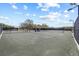 Outdoor tennis court featuring well-maintained surface, net, fencing, lighting, and covered seating area at 888 Royal Birkdale Dr, Tarpon Springs, FL 34688