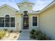 Close-up of a house entrance with a red door, manicured bushes, and stone landscaping at 9010 Penelope Dr, Weeki Wachee, FL 34613