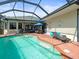 Backyard pool with brick paver deck, chaise lounge, and umbrella covered table and chairs at 9010 Penelope Dr, Weeki Wachee, FL 34613