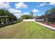 Beautifully landscaped backyard with a screened-in pool, lush lawn, and private wooden dock at 9088 Gallup Cir, Spring Hill, FL 34608