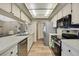Long galley kitchen with white countertops, stainless steel appliances, and ample cabinet storage space at 9088 Gallup Cir, Spring Hill, FL 34608