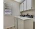 Well lit laundry room with window and storage cabinets above laundry appliances at 9088 Gallup Cir, Spring Hill, FL 34608