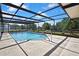 A large screened pool with clear blue water sits on a concrete deck and surrounded by landscaping at 9088 Gallup Cir, Spring Hill, FL 34608