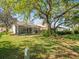 A partially obscured backyard featuring mature landscaping and an enclosed patio at 9355 French Quarters Cir, Weeki Wachee, FL 34613