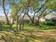 Expansive backyard featuring a lush lawn, mature trees, and a screened-in patio for outdoor relaxation at 9355 French Quarters Cir, Weeki Wachee, FL 34613