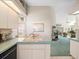 Kitchen has light blue countertops, white cabinetry and views into the living space beyond at 9355 French Quarters Cir, Weeki Wachee, FL 34613