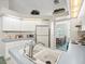 Bright kitchen featuring white cabinetry, stainless steel faucet and breakfast nook in the adjacent room at 9355 French Quarters Cir, Weeki Wachee, FL 34613