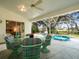 A screened in patio with a hot tub, and a wicker dining set with a view of the backyard at 9355 French Quarters Cir, Weeki Wachee, FL 34613