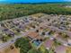 Aerial view of homes in community, featuring a lake and a dense forest backdrop at 10106 Tolman Dr, Hudson, FL 34667